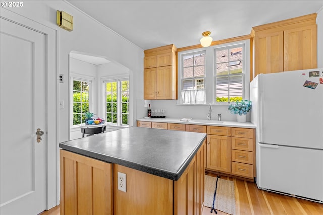 7311 SE 31st Ave, Portland, OR 97202 - kitchen with freestanding refrigerator, light wood finished floors, arched walkways, a center island, and dark countertops