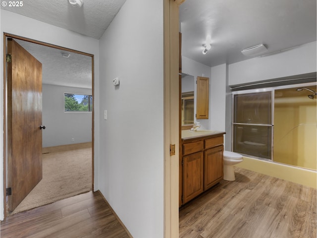 5327 SE Ogden St, Portland, OR 97206 - full bath with vanity, toilet, a textured ceiling, wood finished floors, and a shower with door