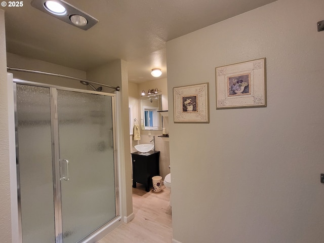 bathroom with vanity, toilet, a shower with door, and wood-type flooring