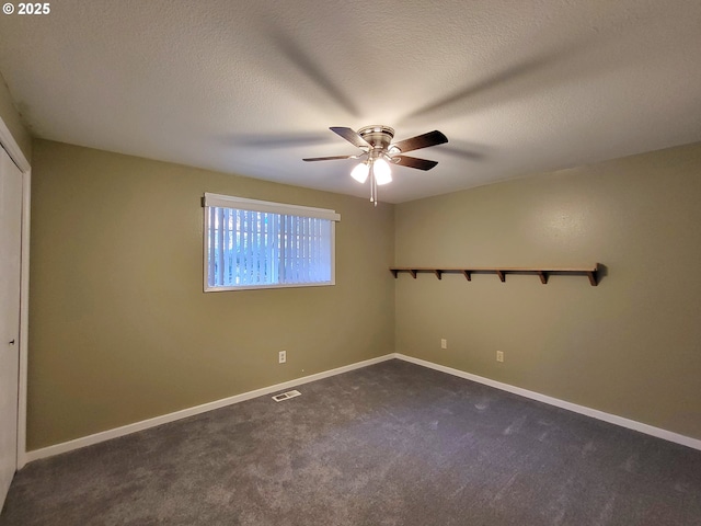 spare room with ceiling fan, dark carpet, and a textured ceiling