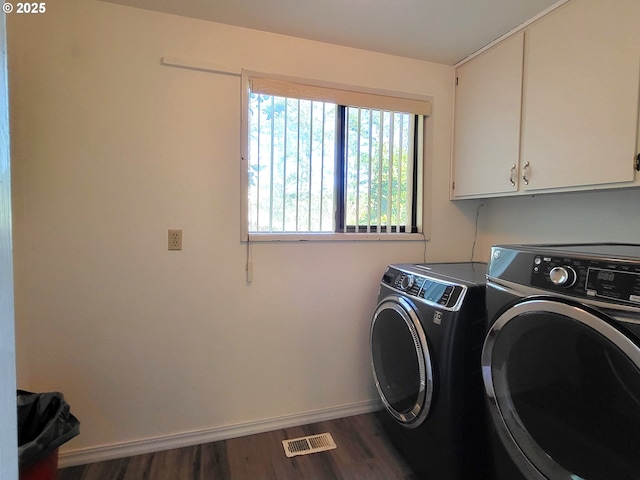 clothes washing area featuring dark wood-type flooring, cabinets, and washing machine and dryer