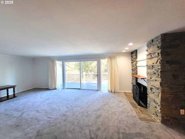 unfurnished living room featuring a stone fireplace, light carpet, and a textured ceiling