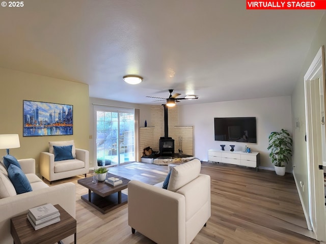 living room featuring ceiling fan, light hardwood / wood-style flooring, and a wood stove