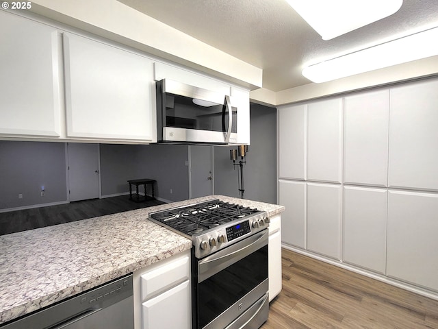 kitchen with stainless steel appliances, white cabinets, and light wood-type flooring