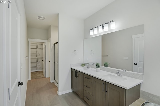 full bathroom featuring double vanity, a walk in closet, and a stall shower