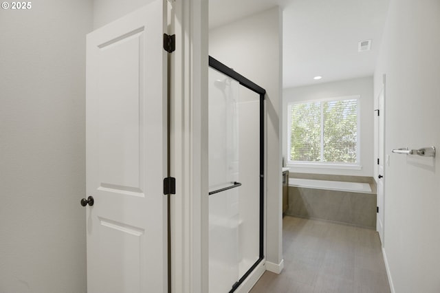 bathroom with a stall shower, baseboards, a bath, and recessed lighting
