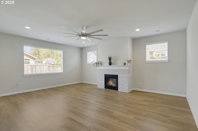 unfurnished living room with light wood-style flooring, ceiling fan, a glass covered fireplace, recessed lighting, and baseboards