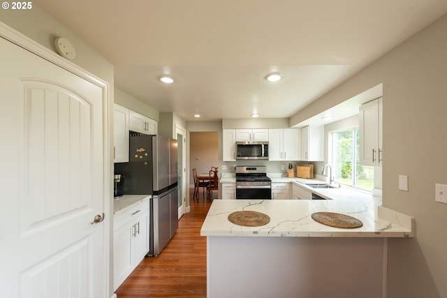 1919 SE 22nd Pl, Renton, WA 98055 - kitchen with stainless steel appliances, a sink, wood finished floors, light stone countertops, and a peninsula