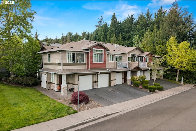 view of property with an attached garage, stone siding, driveway, a front yard, and a balcony