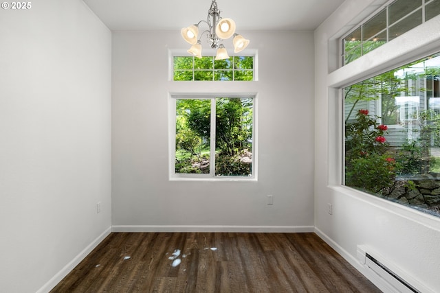 unfurnished dining area featuring a baseboard heating unit, a chandelier, wood finished floors, and baseboards