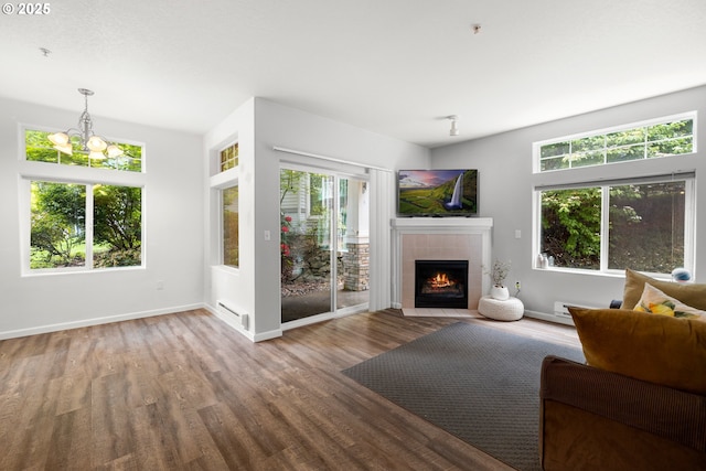 living room featuring wood finished floors, a tiled fireplace, baseboards, and a baseboard heating unit
