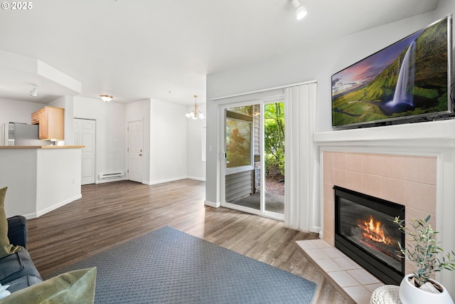 living room featuring wood finished floors, a tile fireplace, baseboards, and baseboard heating