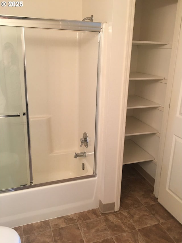 bathroom featuring toilet and combined bath / shower with glass door