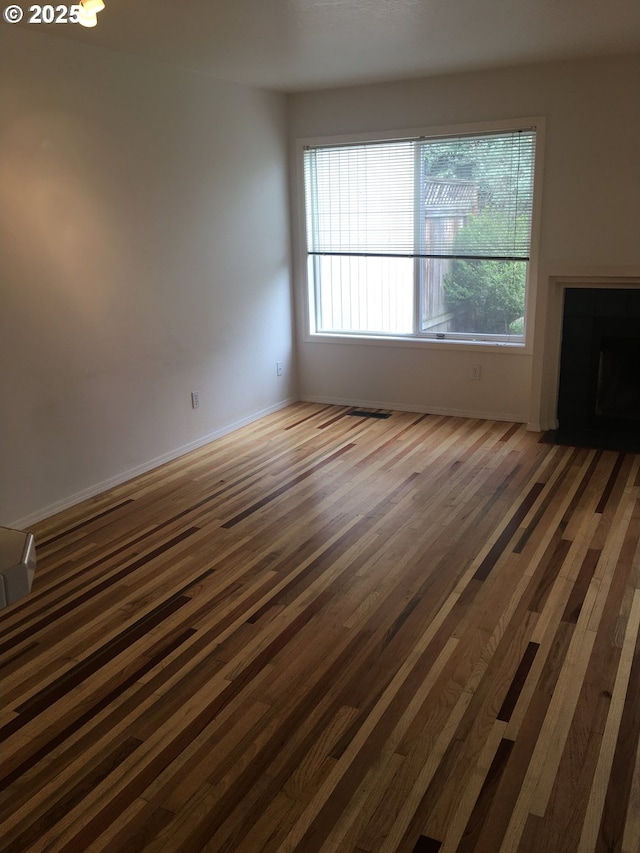 unfurnished living room with a fireplace, a healthy amount of sunlight, and dark hardwood / wood-style floors