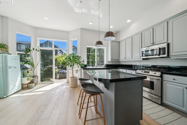 kitchen with a sink, dark countertops, stainless steel appliances, and a healthy amount of sunlight