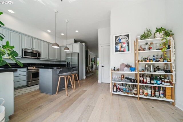 kitchen with a breakfast bar area, dark countertops, light wood finished floors, stainless steel appliances, and recessed lighting
