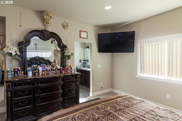 bedroom featuring baseboards, multiple windows, ensuite bathroom, and light colored carpet