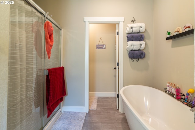 bathroom featuring a stall shower, a freestanding tub, and baseboards