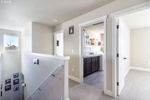 hall with washer / dryer, baseboards, an upstairs landing, and light colored carpet