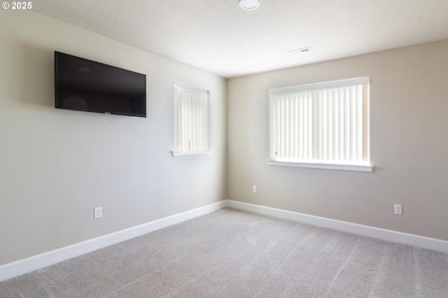 carpeted spare room featuring visible vents, a textured ceiling, and baseboards