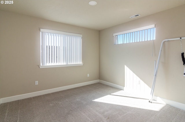 spare room featuring carpet flooring, visible vents, and baseboards