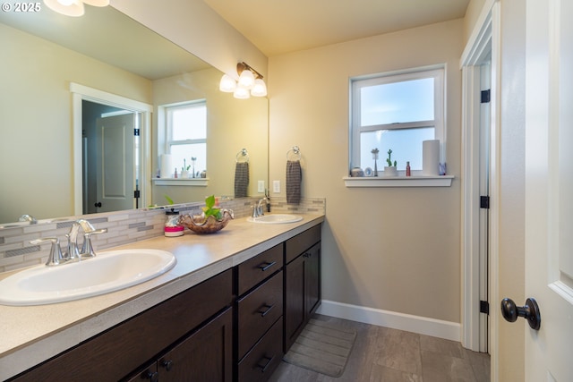 bathroom featuring double vanity, tasteful backsplash, a sink, and baseboards