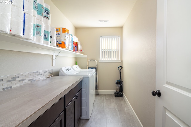 washroom with washing machine and dryer, visible vents, cabinet space, and baseboards