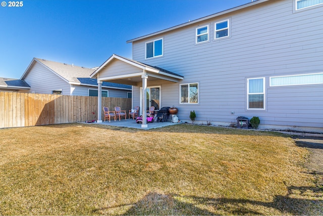 rear view of property featuring a patio, a lawn, and fence