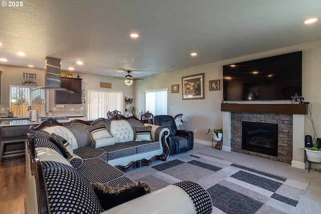 living room featuring recessed lighting, ceiling fan, a stone fireplace, and baseboards