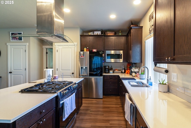 kitchen featuring island range hood, stainless steel appliances, dark brown cabinets, light countertops, and a sink