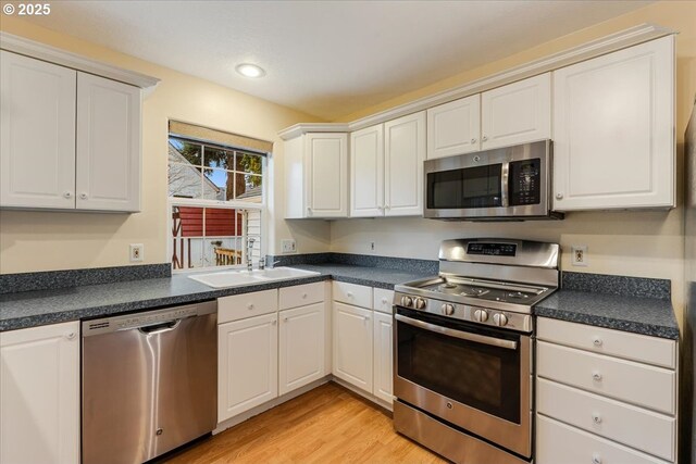 kitchen with a sink, dark countertops, and appliances with stainless steel finishes