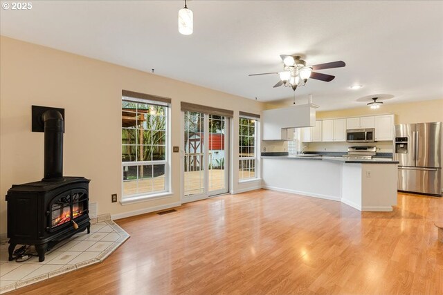 kitchen with white cabinets, visible vents, a peninsula, appliances with stainless steel finishes, and light wood-type flooring