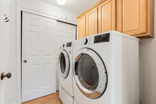 laundry room featuring washer and dryer, light wood-style floors, and cabinet space