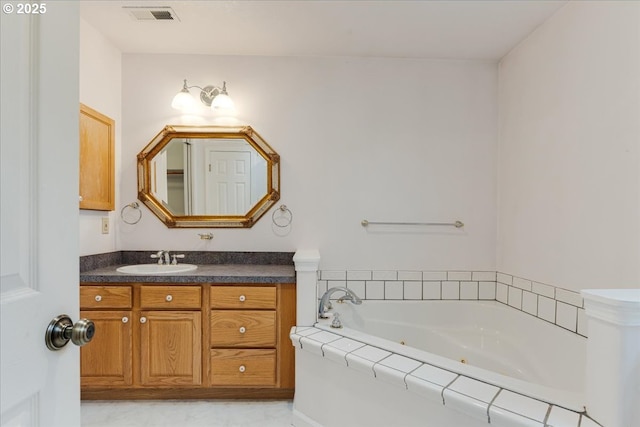 bathroom featuring a tub with jets, vanity, and visible vents