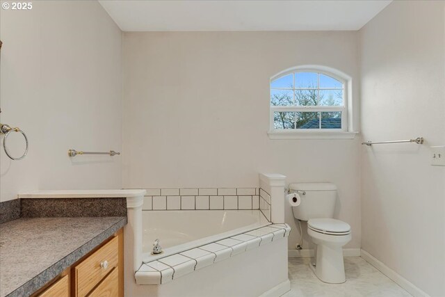full bath with toilet, vanity, baseboards, and a garden tub