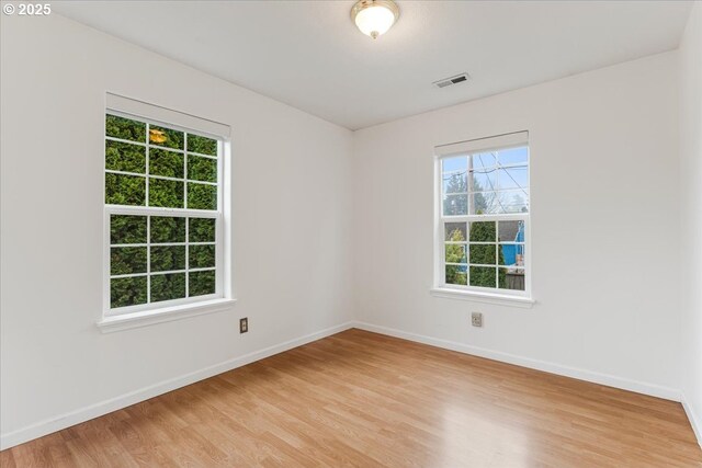 spare room featuring light wood finished floors, baseboards, and visible vents