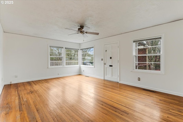 interior space featuring a wealth of natural light, light wood-style floors, ceiling fan, and baseboards