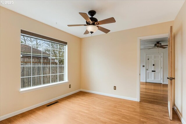empty room with light wood finished floors, baseboards, visible vents, and ceiling fan