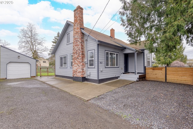 exterior space with fence, driveway, a chimney, an outdoor structure, and a garage