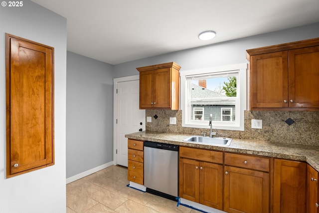 kitchen featuring baseboards, a sink, decorative backsplash, dishwasher, and brown cabinets