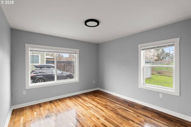 spare room with baseboards and hardwood / wood-style flooring