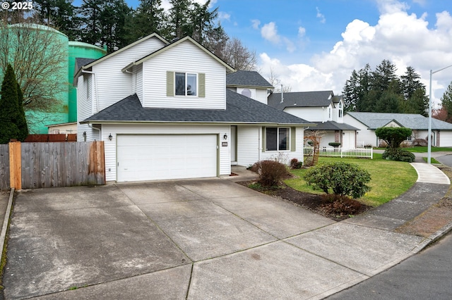 traditional-style house with concrete driveway, a shingled roof, an attached garage, and fence