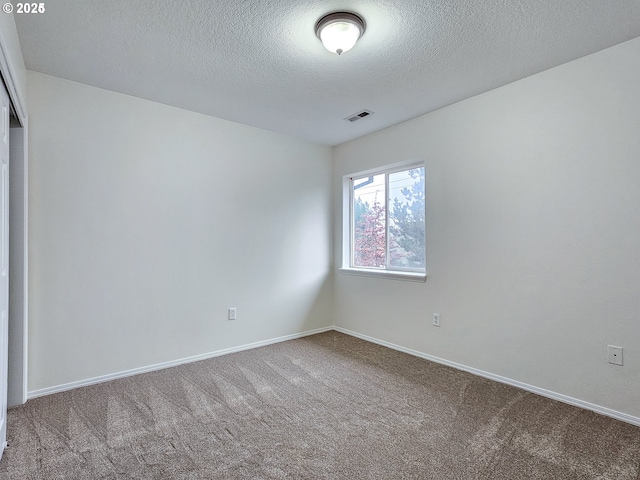 carpeted spare room featuring a textured ceiling, visible vents, and baseboards