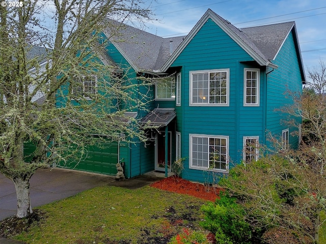 traditional home featuring concrete driveway, a shingled roof, and an attached garage