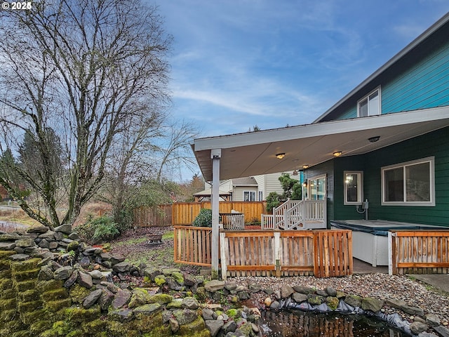 deck with a hot tub and fence