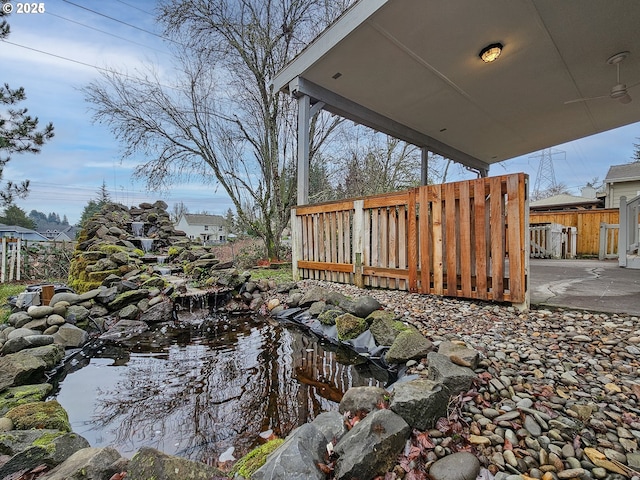 view of yard with a small pond, fence, and a patio