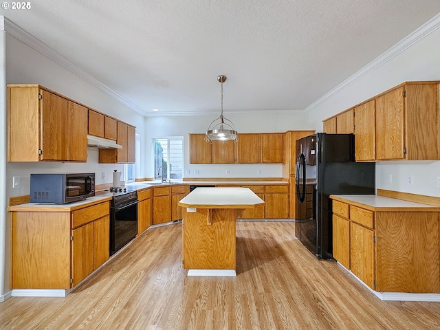 kitchen with brown cabinetry, a kitchen island, under cabinet range hood, light countertops, and black appliances