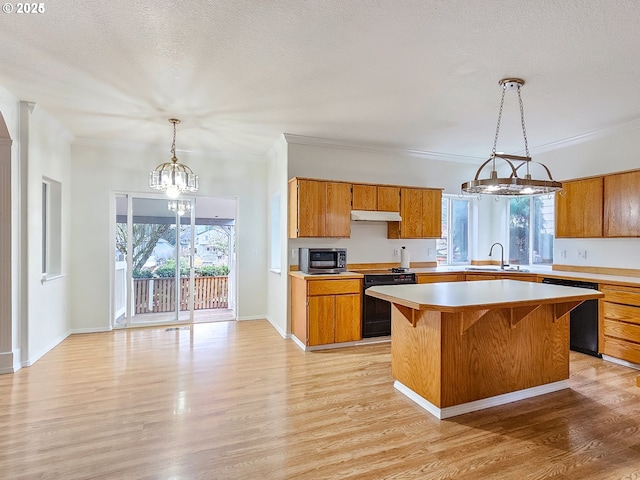 kitchen with brown cabinets, light countertops, a sink, light wood-type flooring, and black appliances