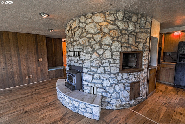77993 Point Adams Rd, Clatskanie, OR 97016 - unfurnished living room featuring a wood stove, hardwood / wood-style flooring, a fireplace, and wooden walls