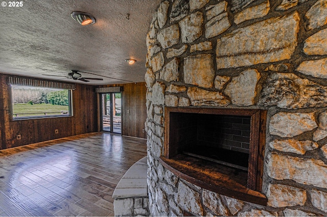 77993 Point Adams Rd, Clatskanie, OR 97016 - unfurnished living room featuring a fireplace, a ceiling fan, wood finished floors, a textured ceiling, and wooden walls